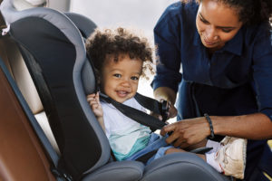 Cute baby with mother checking the safety of the car seat
