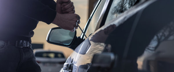 Auto thief in black balaclava trying to break into car