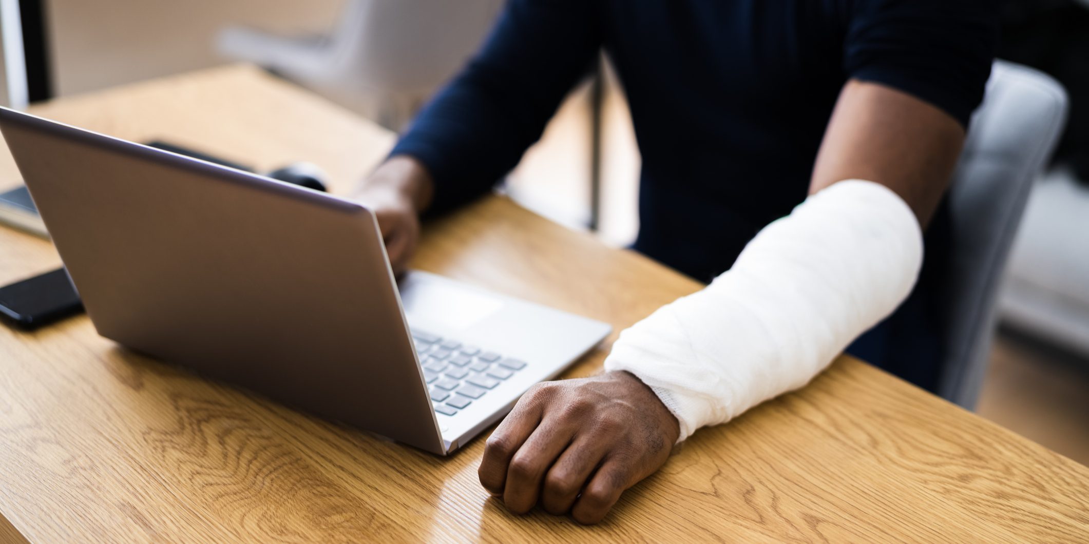 Injured Worker Compensation. Broken Arm African Man On Computer