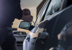 Auto thief in black balaclava trying to break into car